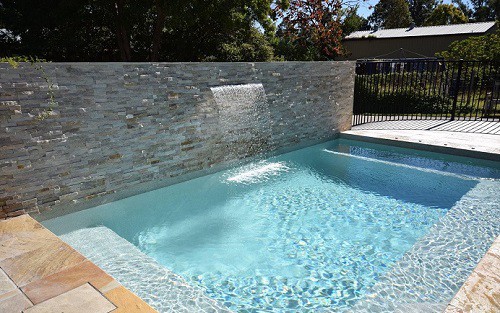 An inviting looking pool with waterfall feature with the Pebble Range pool interior